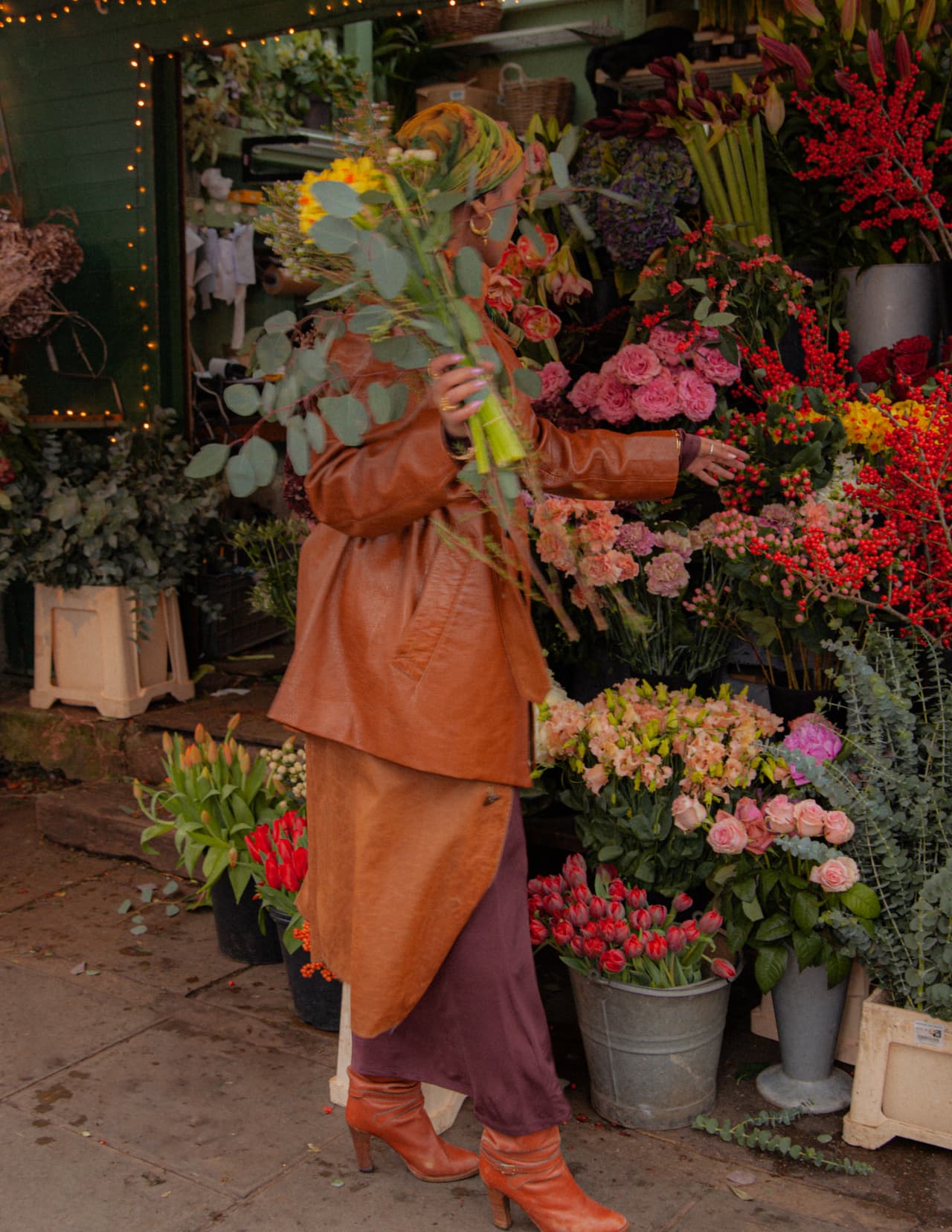 A florist carrying eucalyptus through a flower market